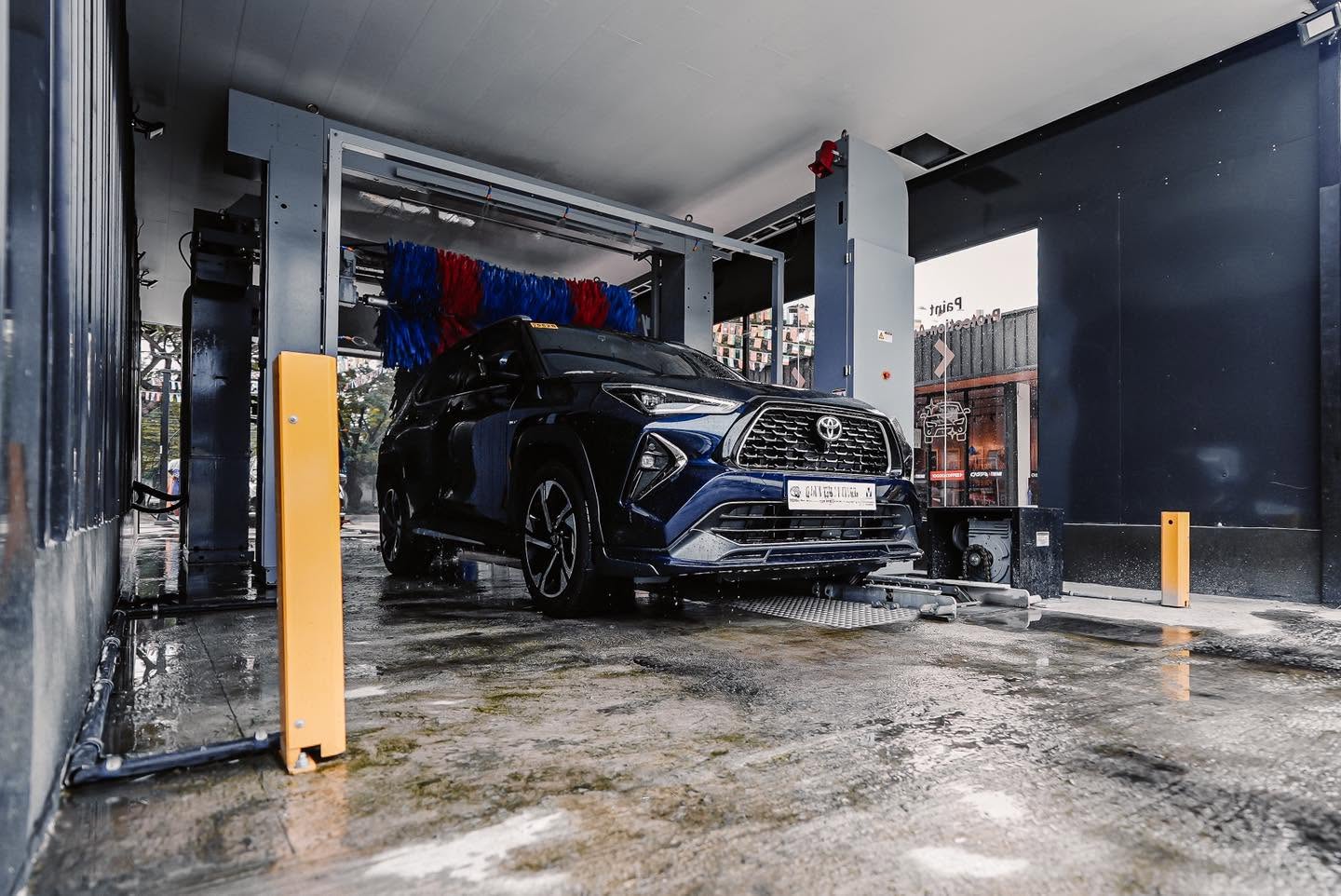 A dark blue SUV inside the CASPA Xtreme automatic wash bay with a glossy wet floor